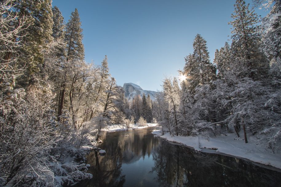 Yosemite valley covered in snow, Half dome in the distance a river in the foreground- Jeremy Bishop | Unsplash